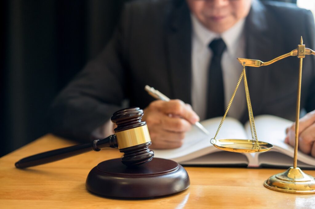 Male lawyer working with contract papers and reading law book in a courtroom