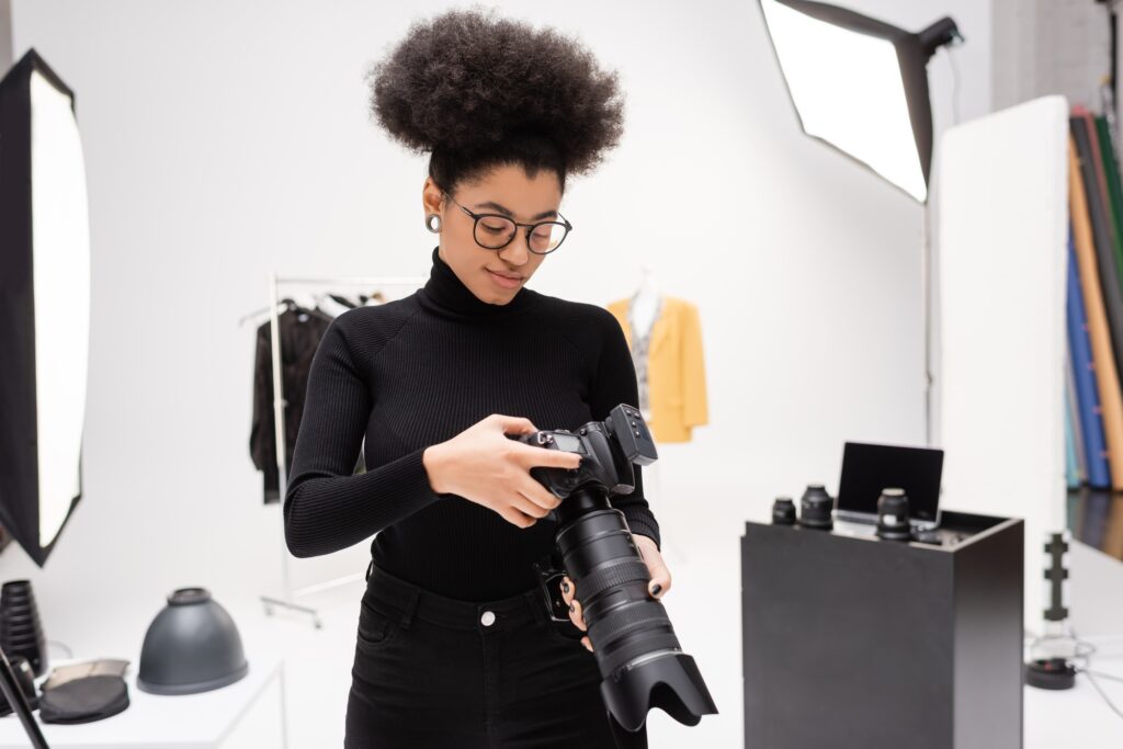 african american photographer in eyeglasses and black turtleneck looking at professional digital